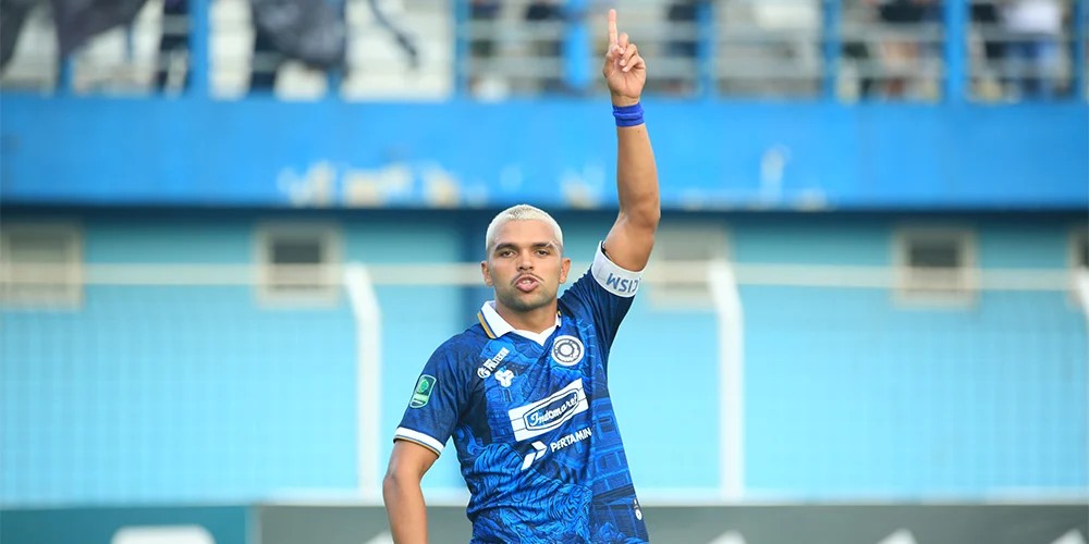 Stadium packed with fans holding blue scarves during a night match
