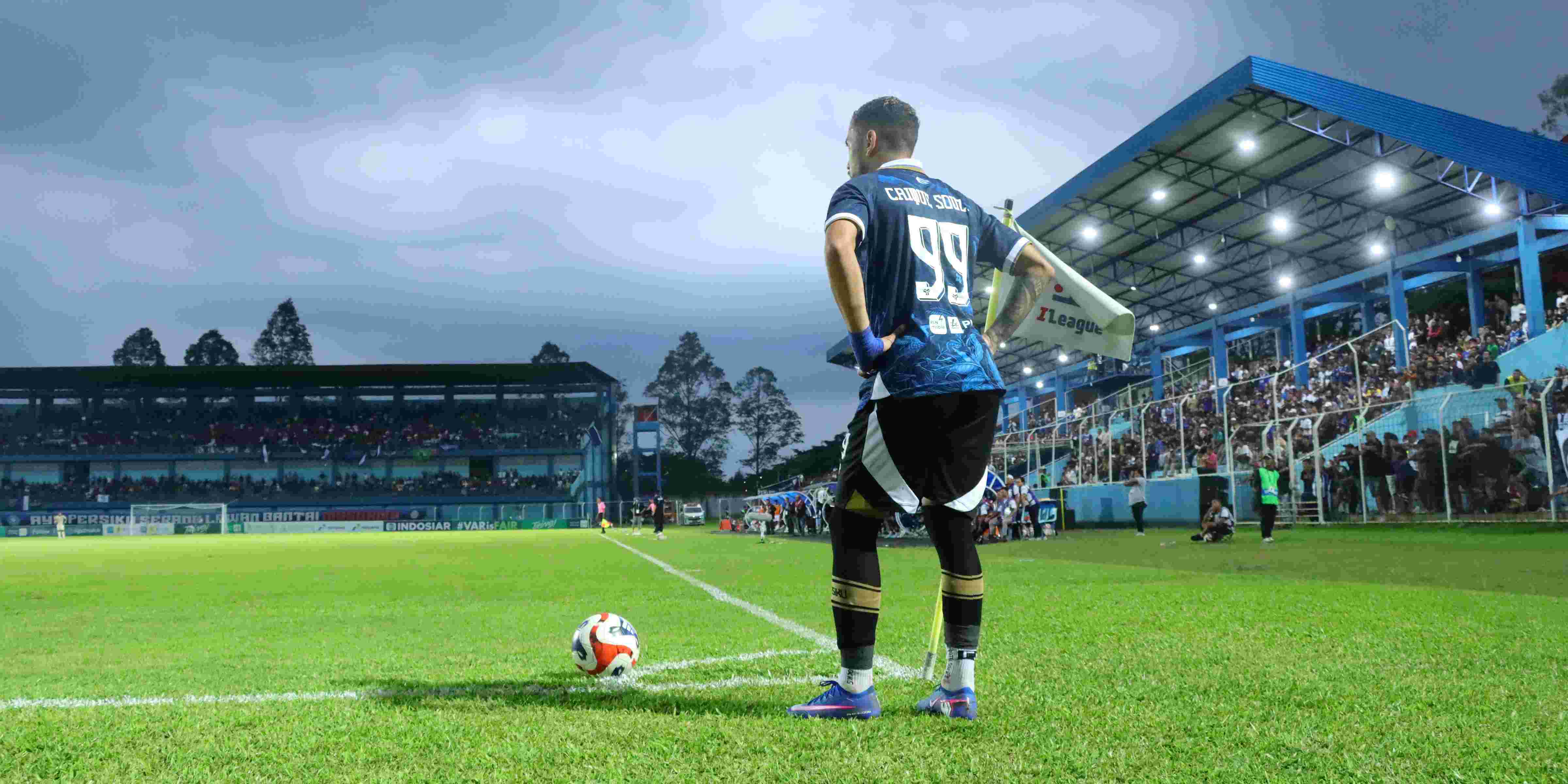 Stadium packed with fans holding blue scarves during a night match
